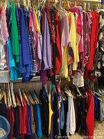 Colorful assortment of women's blouses and tops on hangers in shades of green, blue, pink, purple, yellow, and more.