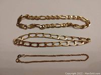 Three gold bracelets arranged side by side on white background.