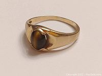 Close-up angled photo of the 10k yellow gold ring with the oval tiger's eye stone showing band and stone details.