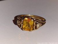 Ring top angled view showing yellow center stone and clear side stones