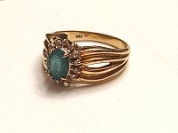 Three-quarter view showing oval green stone and halo of clear accents on split shank