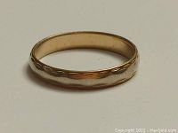 Close-up image of the 14k yellow gold wedding band showing the engraved oval pattern on the outer surface.