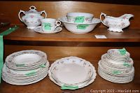 Top shelf with cream and sugar set, gravy boat, bowl and cup on saucer along with some bowls and plates below.