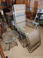 Photo of beige zero gravity lounge chair and gray metal side table in basement setting