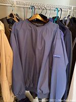 Blue long sleeve pullover jacket hanging on rack with other jackets