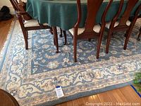 Blue Oriental style rug under dining table, showing overall pattern and size context.