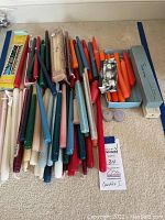 Full lot of assorted taper candles in various sizes, colors, and some in original packaging laid out on a carpeted floor.