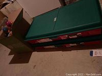 Two large green plastic storage tubs stacked on the floor.