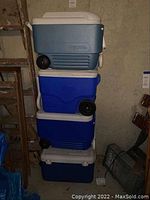 Four coolers stacked vertically, showing the variety in color and model, mainly Igloo.