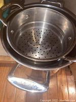 Photo of Cuisinart stainless steel pot containing metal steamer insert showing perforated holes in steamer and pot handles