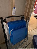Blue folding chairs stacked against wall on basement floor