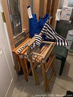 Photo showing three wooden directors chairs with blue and white striped fabric outdoor sports chairs and a wooden stool/table