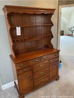 Full view of the 2-piece solid wood shaker style hutch showing the medium brown finish, scalloped top edge, two open shelves with rail, and lower storage section with drawers and cabinets.