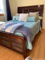 Front right diagonal view of queen bed frame fully assembled with linens and pillows