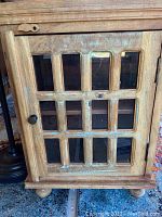 Front view of cabinet door showing 12 glass panels and black knob with latch.