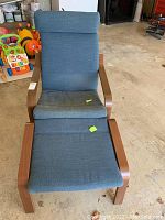 Front view of wood frame lounge chair with blue fabric cushions, including separate headrest, and matching ottoman in same style and fabric.