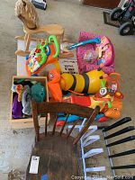 Top-down view showing wooden rocking chair, yellow bee ride-on toy, orange animal ride-on toy, pink Disney Princesses bench, colorful musical toy and box of plush toys.