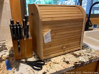 Calphalon knife set in wooden block next to wooden bread box on kitchen counter