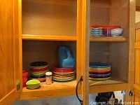 Cabinet shelf with stacked small bowls, dinner plates, turquoise pitcher
