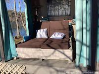 Front view of double lounger with brown cushions and two decorative pillows.