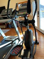 Front view of elliptical and adjacent treadmill, showing frame and console