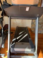 Front view of treadmill showing gray frame, black belt, and desktop workstation