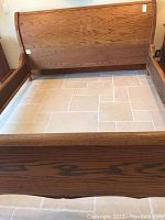 Full view of the oak bed frame headboard and footboard showing solid wood construction and surface scratches.