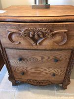 Front view of oak nightstand showing carved acorn motif and two drawers