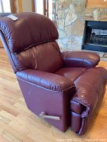 Photo of red faux leather La-Z-Boy manual recliner from an angle showing seat and armrest.