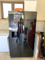 Front view of the black Kenmore side-by-side refrigerator showing both doors and dispenser area.
