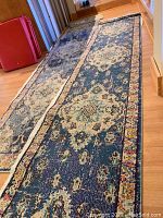 Pair of two long rectangular Safavieh Monaco runners in navy blue with floral medallion patterns and multicolor borders, laid on hardwood floor.
