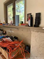 Shelf with orange extension cord coiled, boxes underneath, and assorted paint supplies and hardware items