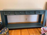 Front view of the teal console table showing four drawers and bottom shelf