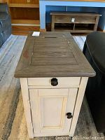 Full top view of the wooden side table showing natural wood finish top with visible damage, and a white painted drawer and door below.