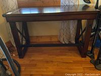 Full side angled view of wood and metal table showing metal legs and wood top