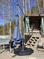 Full view of the blue cantilever umbrella on the patio with nearby outdoor chairs and wooden deck.