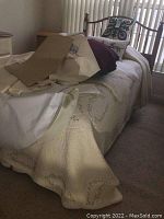 View of twin bed with beige linens, mattress and pillows, bed frame partially visible under linens.