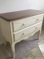Front and side view of Ethan Allen dresser showing two drawers, cream body, wood top, curved legs, and decorative pulls.