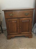 Front view of wooden Ethan Allen nightstand with cabinet and drawer, showing brass hardware and classic design.