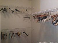 Photo showing a section of a closet corner with wire shelves and an assortment of multiple types of hangers including black plastic and a few wooden ones.