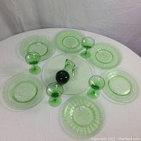 View of full lot including all plates, stemware glasses, and handled cake plate with green handle. Green apple included for size reference.