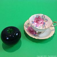 Teacup and saucer next to green apple for scale
