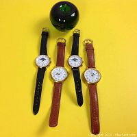 Overhead view of four watches arranged with green apple for scale