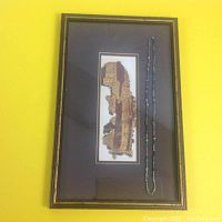Full view of framed fragment on left and bead necklace on right