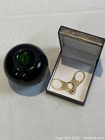 Gold snips in presentation box next to a round size reference object