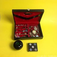 Jewelry box open showing red velvet interior and assorted cufflinks and watches
