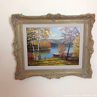 Full view of one framed landscape painting showing birch trees by a lake in fall colors.