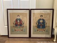 Pair of framed ancestor portrait paintings leaning side by side against white door