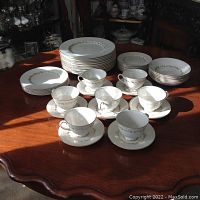 Overview of the porcelain dinnerware set arranged on a wooden table including plates, bowls, cups, and saucers.