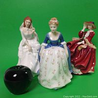 Photo showing all three Royal Doulton figurines together with a black apple for size reference.